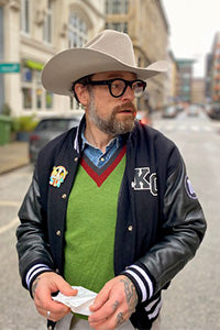 Mann mit Brille und Cowboyhut in der Mitte einer Straße